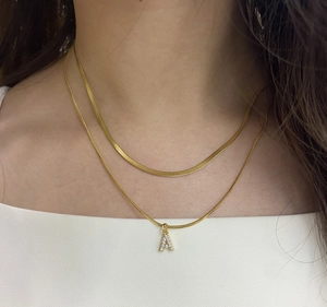 Close-up of a gold double-layer snake chain necklace with a micro-pave letter A pendant