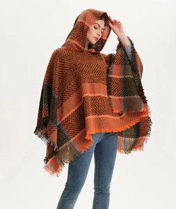 Detail of herringbone pattern hooded poncho with fringe trim in orange and brown