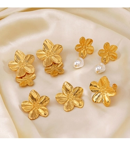 Golden flower earrings with pearls displayed on beige silk fabric background