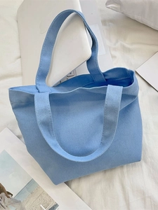 Minimalist sky blue canvas tote bag on white bedding with a laptop background