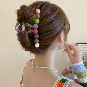Rear view of a model wearing a clear claw clip with colorful beads for a bun hairstyle
