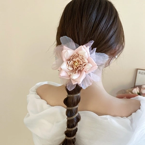 Détail d'un grand élastique à cheveux fleur rose avec des pétales en mousseline et organza