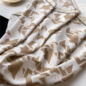 Détail de la texture satinée et des lettres géométriques sur le foulard en soie de luxe