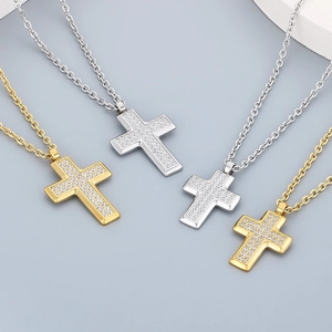 Cross pendant necklace in gold and silver with CZ stones on a gray background