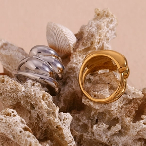 Detailed view of silver and gold interlaced wave dome rings on coral stone