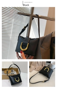 Detail of black leather shoulder bag featuring a signature gold U-shaped metal buckle hardware
