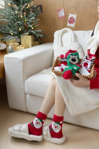 Detail of soft coral fleece Christmas socks featuring Santa Claus and reindeer patterns