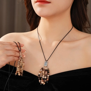 Detail of beaded necklace with natural stones in earthy tones and sleek black cord