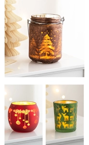 Detailed view of three festive glass candle holders with reindeer and snowflake patterns