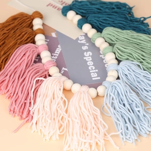 Detail shot of boho wood bead garland with colorful cotton tassels on pink background