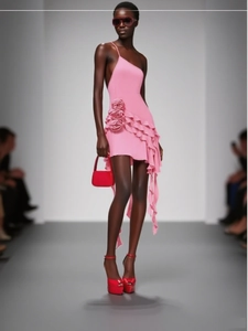 Detail of pink one-shoulder dress featuring 3D floral accent and layered ruffles at runway