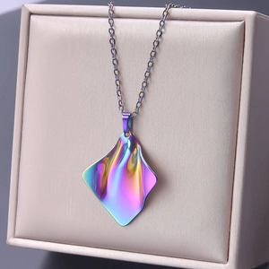 Detail of an iridescent irregular geometric pendant with liquid metal texture on a beige box