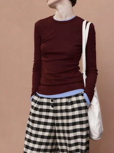 Detail view of burgundy long sleeve knit top paired with black and white checkered trousers
