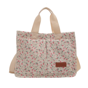 Floral canvas tote bag with front pockets and adjustable straps for crossbody use