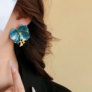 Close-up of vintage blue flower earring with gold bee detail worn by a model