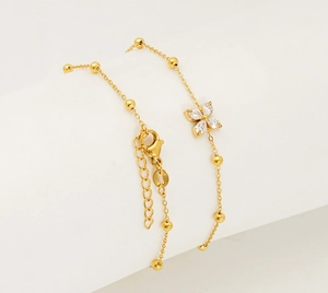 Detailed macro view of gold titanium steel bracelet with clover zircon charm and bead chain