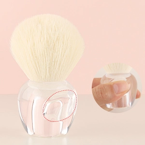 Detailed view of clear handle makeup brush with ergonomic thumb groove and soft bristles