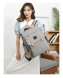 Side view of a large grey fabric diaper backpack with leather details on a female model
