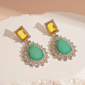 Macro detail of teardrop earrings with yellow and green gems and sparkling crystals