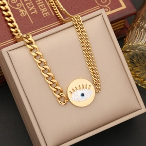 Close-up of gold Cuban chain bracelet with crystal evil eye pendant on a beige jewelry box