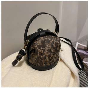 Detail of leopard print cylinder bag with black leather trim and gold metal hardware