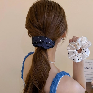 Close-up of elegant satin polka dot scrunchies in navy blue and cream white finishes