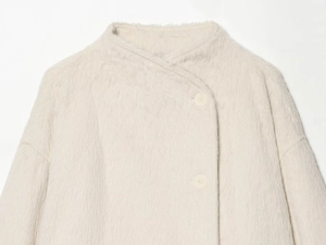 Close-up of fluffy cream faux fur coat featuring a soft texture and matching buttons