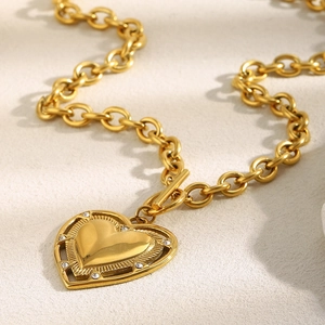 Détail d'un collier à grosse chaîne en or 18 carats avec un pendentif cœur serti de diamants