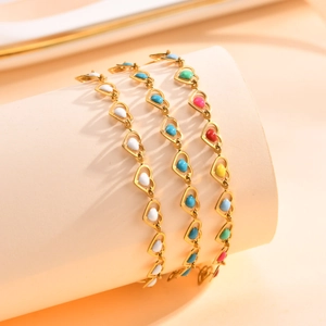 Close-up of gold chain bracelets with colorful enamel heart charms on a stand