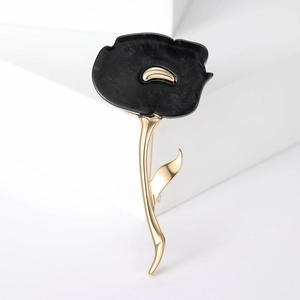 Detailed view of an elegant black and gold flower brooch on a white geometric background