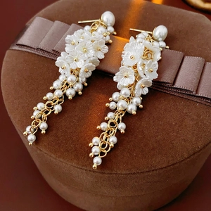 Detail of floral resin earrings with hanging pearls on a ribbon jewelry box