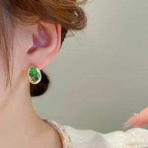 Close-up of vintage irregular gold earrings with oval green iridescent shell inlay