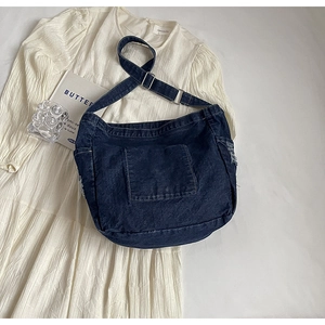 Gros plan d'un sac cabas en jean foncé avec bords effilochés et sangle à boucle réglable