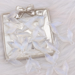 Close-up of glittery acrylic mermaid tail pendants on a soft white plush background