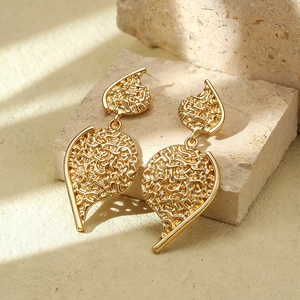 Detailed view of golden leaf-shaped earrings with textured finish on a stone