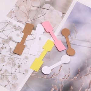 Colorful dumbbell-shaped paper jewelry price tags scattered on floral background
