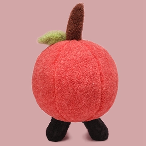 Close-up of soft red apple plush toy with fluffy sherpa texture and green leaf detail