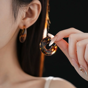 Close-up of leopard print resin C-shaped earrings worn by a model in deep tones