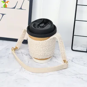 Detail of soft lamb wool coffee cup sleeve with cream leather handle on a desk