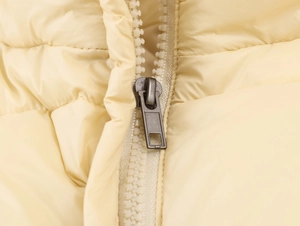 Macro shot of high-quality zipper and polyester windproof fabric on a light beige jacket