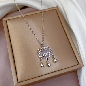 Detail of silver long life lock pendant with white jade inlay and small bells on silk