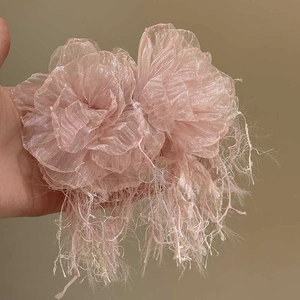 Close-up of pink fabric flower earrings with elegant tassels and shimmering silver pins