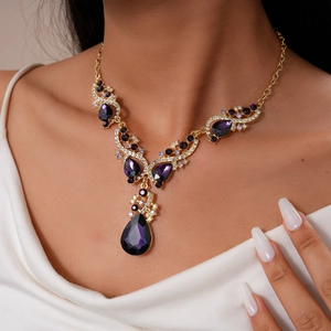 Detailed close-up of a vintage golden necklace set with purple teardrop gemstones and crystals
