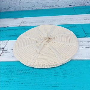 Top view of cream white chunky knit beret showing circular texture and top stem detail