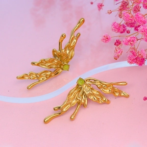 Golden butterfly wing earrings with pale green natural stones on soft pink background