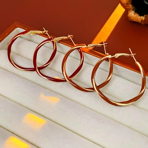Detailed macro of twisted gold enamel hoop earrings in dark red and light brown shades