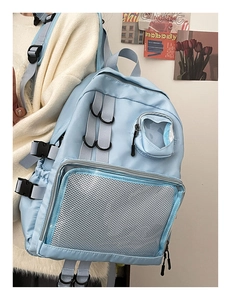 Detail of light blue nylon backpack featuring breathable mesh front pocket and side buckles