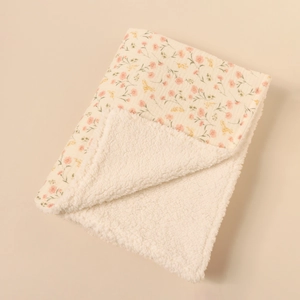 Detail of baby floral muslin blanket with thick white sherpa fleece lining and soft texture