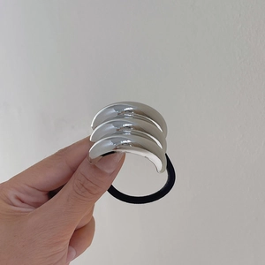 Detail of silver crescent metal pieces on a high-elasticity black hair tie for women