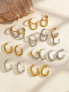 Polished two-tone C-shaped hoop earrings in gold and silver finish displayed on textured surface